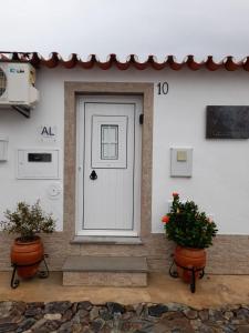 a white front door of a house with two plants at Casa do Celeiro - Monsaraz in Monsaraz