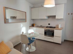 een keuken met witte kasten en een tafel met stoelen bij Mind Tiny Home in Rho