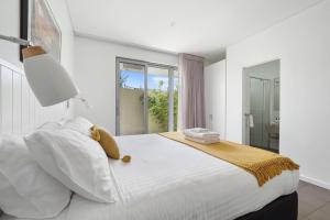 a white bedroom with a large bed with a lamp at Alouarn Apartments in Augusta