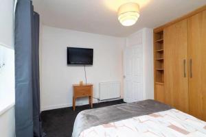 a bedroom with a bed and a tv on a wall at Light-luxury Flat in Glasgow