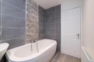 a bathroom with a white tub and a white door at Light-luxury Flat in Glasgow