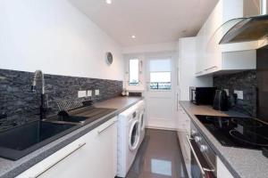 a kitchen with a sink and a washing machine at Light-luxury Flat in Glasgow