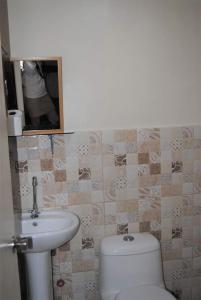 La salle de bains est pourvue de toilettes blanches et d'un lavabo. dans l'établissement Cozy Inn Mactan, à Mactan