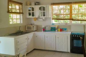 een witte keuken met een fornuis en een magnetron bij StarFish Apartment in Port Elizabeth