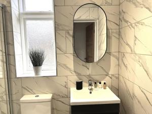 a white bathroom with a sink and a mirror at The Ivanhoe Apartment in Rothley