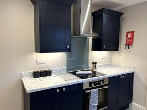 eine Küche mit blauen Schränken und einer Arbeitsplatte in der Unterkunft The Ivanhoe Apartment in Rothley