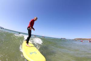 a man riding a wave on a surfboard in the ocean at Gwithian Holidays in Hayle