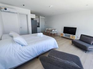 um quarto com uma cama e uma cadeira e uma televisão em SYRAH Premium B2 - Piscina privada con vista al mar by depptö em Punta del Este