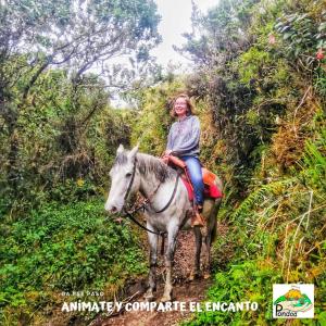 Una donna che cavalca un cavallo lungo un sentiero di Hospedaje Pondoa - Baños de Agua a Baños