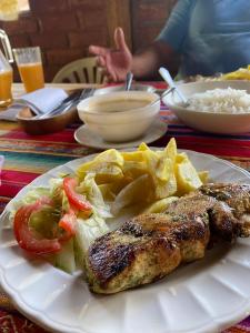 un plato de comida con carne y patatas fritas y arroz en Hospedaje Pondoa - Baños de Agua, en Baños