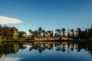 una casa se refleja en el agua de un lago en A beautiful house in Rothley en Rothley