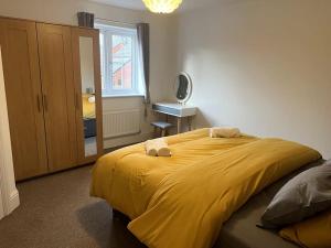 Un dormitorio con una gran cama amarilla con espejo en A beautiful house in Rothley en Rothley