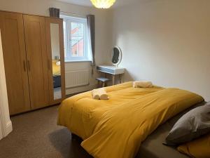 a bedroom with a large yellow bed with a mirror at A beautiful house in Rothley in Rothley