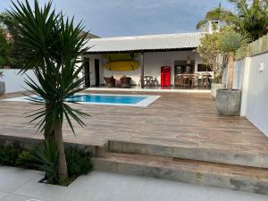 une maison avec une terrasse en bois et une piscine dans l'établissement Casa com piscina Praia dos Molhes, à Torres