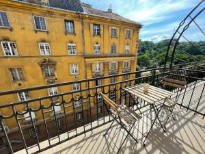 - un balcon avec une table en bois et un bâtiment jaune dans l'établissement Studio27 - Apartment with balcony at the Buda castle, à Budapest