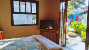 sypialnia z łóżkiem, telewizorem i oknem w obiekcie Geribá Homestay w mieście Búzios
