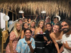 a group of people posing for a picture with a cake at Mango Tree House in Gili Trawangan