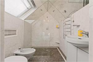 La salle de bains blanche est pourvue de toilettes et d'un lavabo. dans l'établissement The Kirribilli, à Sydney