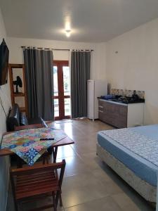 1 dormitorio con cama, mesa y cocina en Recanto das Amendoeiras en Guarda do Embaú