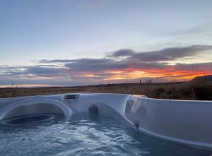 a bath tub in a field with a sunset in the background at Myrarkot Country Home in Selfoss
