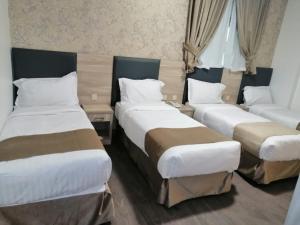 a hotel room with three beds and a couch at Hayah Grand Hotel in Al Madinah