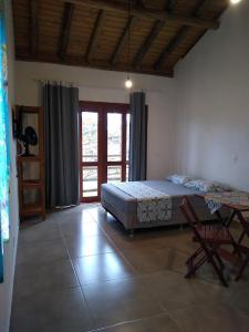 1 dormitorio con 1 cama y 1 silla en Recanto das Amendoeiras, en Guarda do Embaú