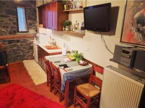 a kitchen with a table and a tv on the wall at Cozy Mountain Villa in P. Agios Athanasios in Palaios Agios Athanasios