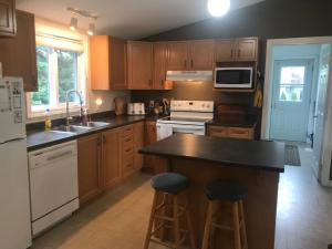 a kitchen with wooden cabinets and a island with bar stools at Perfect 3 bedroom waterfront muskoka cottage in Parry Sound