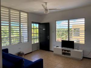 een woonkamer met een tv en een aantal ramen bij Ocean View, Playas del Caribe in Cabo Rojo