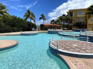 una piscina en un complejo con agua azul y palmeras en Ocean View, Playas del Caribe en Cabo Rojo