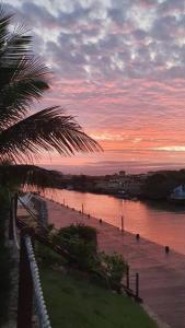 una puesta de sol sobre un cuerpo de agua con una palmera en Melasti Marine House - Casa em Condomínio Familiar com Piscina na Marina de Búzios e Wifi 1G, en Búzios