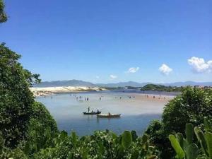 a group of people on a beach with boats in the water at Recanto das Amendoeiras in Guarda do Embaú