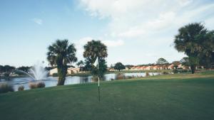 a golf course with a pond and palm trees at Holiday Inn Club Vacations At Orange Lake Resort, an IHG Hotel in Orlando