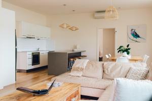 a living room with a couch and a table with a laptop at Exclusive Anglesea River Beach Apartment in Anglesea