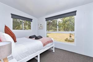 una camera con un letto bianco e due finestre di Wallaby Gully Farm Cottage Peace Quiet Serenity a Ellalong Altre 19 foto