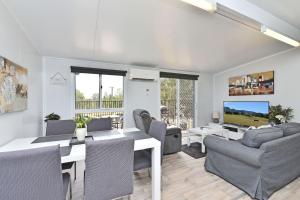 un soggiorno con tavolo, sedie e televisione di Wallaby Gully Farm Cottage Peace Quiet Serenity a Ellalong