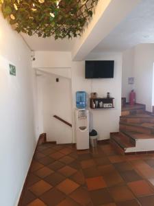 a room with a refrigerator and stairs with a tv at Cemandy Hostal in Villa de Leyva