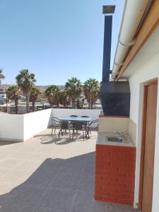 eine Terrasse mit einem Tisch, Stühlen und Palmen in der Unterkunft DepartoCasa2 Premium in Arica