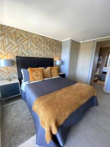 1 dormitorio con 1 cama azul grande con almohadas de color naranja en Departamento Dunas de Concón, en Concón