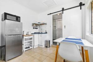 a kitchen with a refrigerator and a table and chairs at The Brick Batch - holiday unit! in Bellara