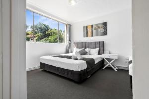 a white bedroom with a bed and a window at The Robert Towns in Townsville