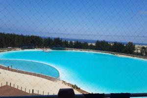 une grande piscine bleue derrière une clôture dans l'établissement Depto con piscina y laguna artificial en Las cruces, à Las Cruces