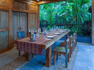ein großer Holztisch mit Stühlen und einem Tisch in der Unterkunft Nienté Bali in Jatiluwih