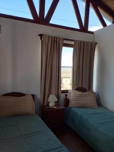 two beds in a room with a window at FREEDOM Iris in Río Gallegos
