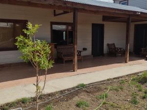 a porch of a house with chairs and a tree at FREEDOM Iris in Río Gallegos