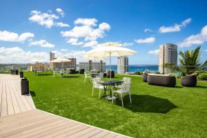 a lawn with tables and chairs and an umbrella at The Bayview Hotel Guam in Tumon