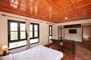 a bedroom with a bed and a desk and windows at Bandipur Bliss-Apartment in Bandipur