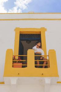 a woman sitting on a balcony of a building at Hostal 1545 in Ríohacha