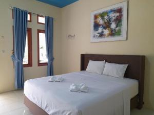 Un dormitorio con una cama con toallas blancas. en Tangkoko Lodge, en Bitung