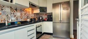 uma cozinha com armários brancos e um frigorífico de aço inoxidável em Casa Próximo ao Centro Agradável e Inteligente em Poços de Caldas